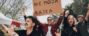 Grupa radosnych osób manifestuje radość z rozwiązania umowy z telefonią komórkową z transparentem Nie moja bajka