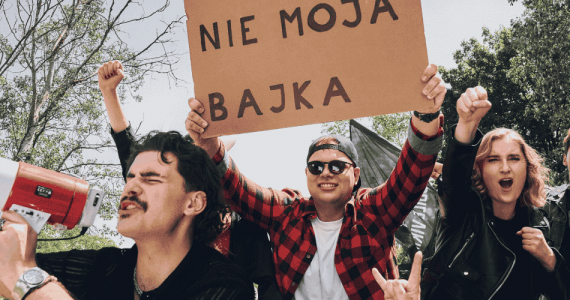Grupa radosnych osób manifestuje radość z rozwiązania umowy z telefonią komórkową z transparentem Nie moja bajka